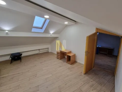 Attic room with wooden flooring, a skylight, and a desk. - image 7