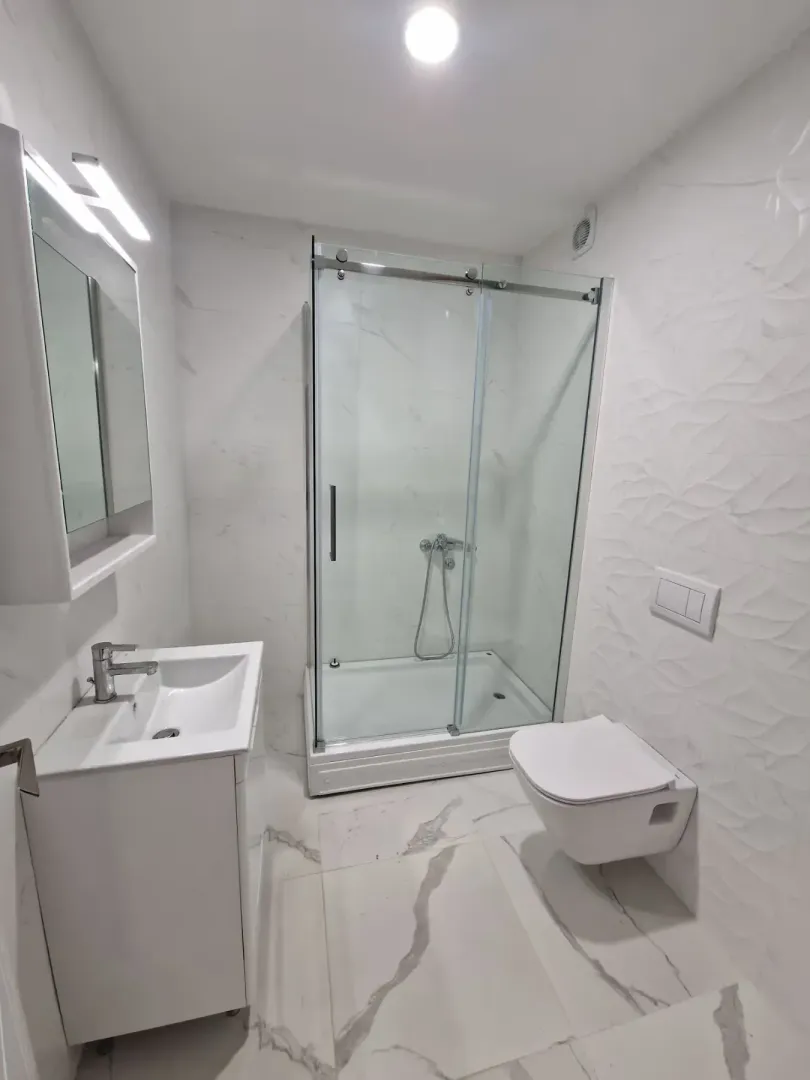 Moderne kupatilo sa tuš kabinom, umivaonikom i ugradnom wc šoljom.