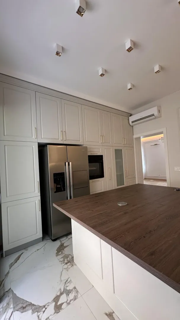 Modern kitchen with a wooden island, built-in appliances, and a large refrigerator.