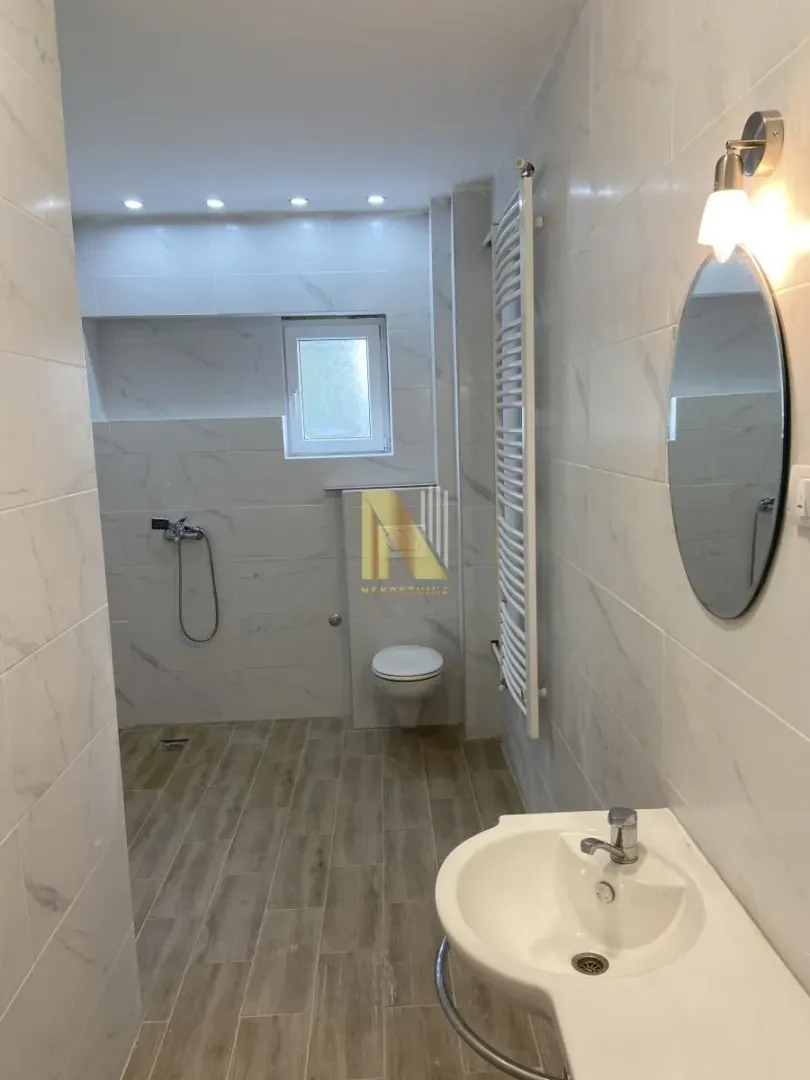 Modern bathroom with a walk-in shower, washbasin, and wall-hung toilet.
