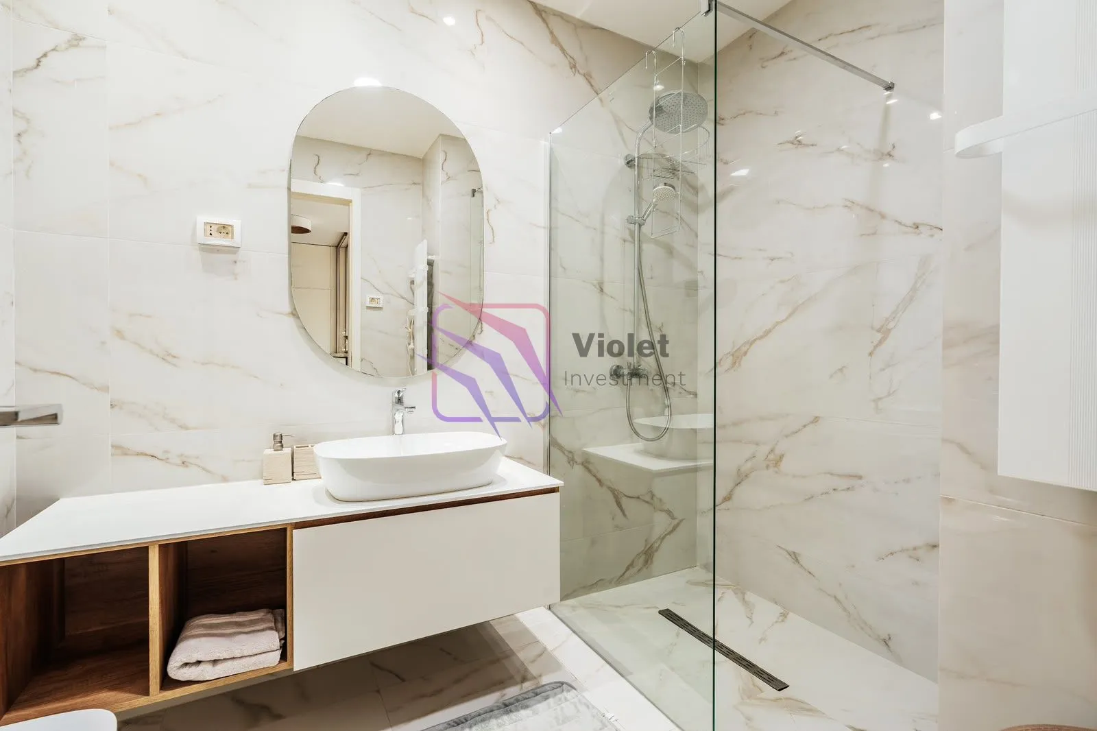 Modern bathroom equipped with a washbasin and a walk-in shower finished with marble-effect tiles.
