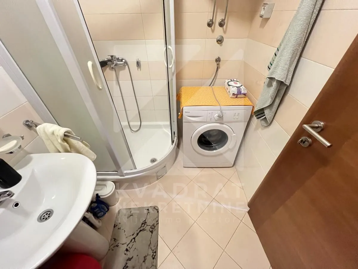 Smaller bathroom with a shower cabin and a washing machine.
