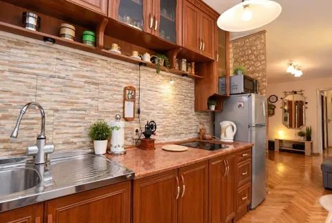 Wooden kitchen with a sink, countertop, and wall cabinets. - image 2