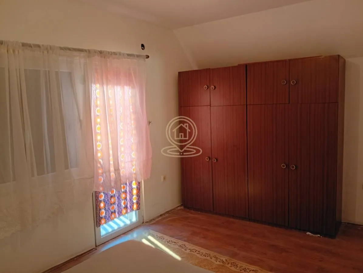 Spavaća soba sa velikim drvenim ormarom i balkonskim vratima.
