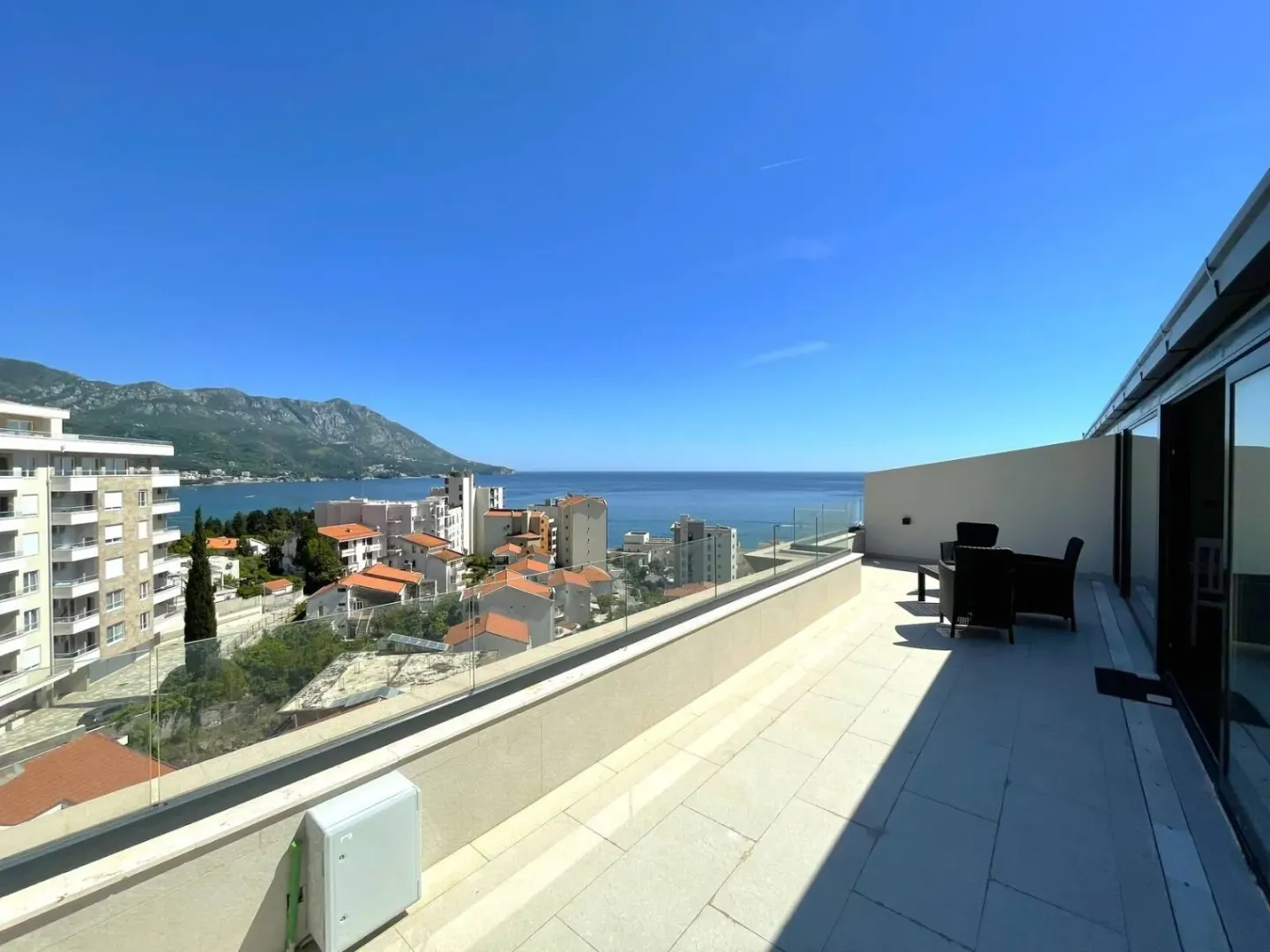 Large terrace with seating furniture and a view of the sea and the city.