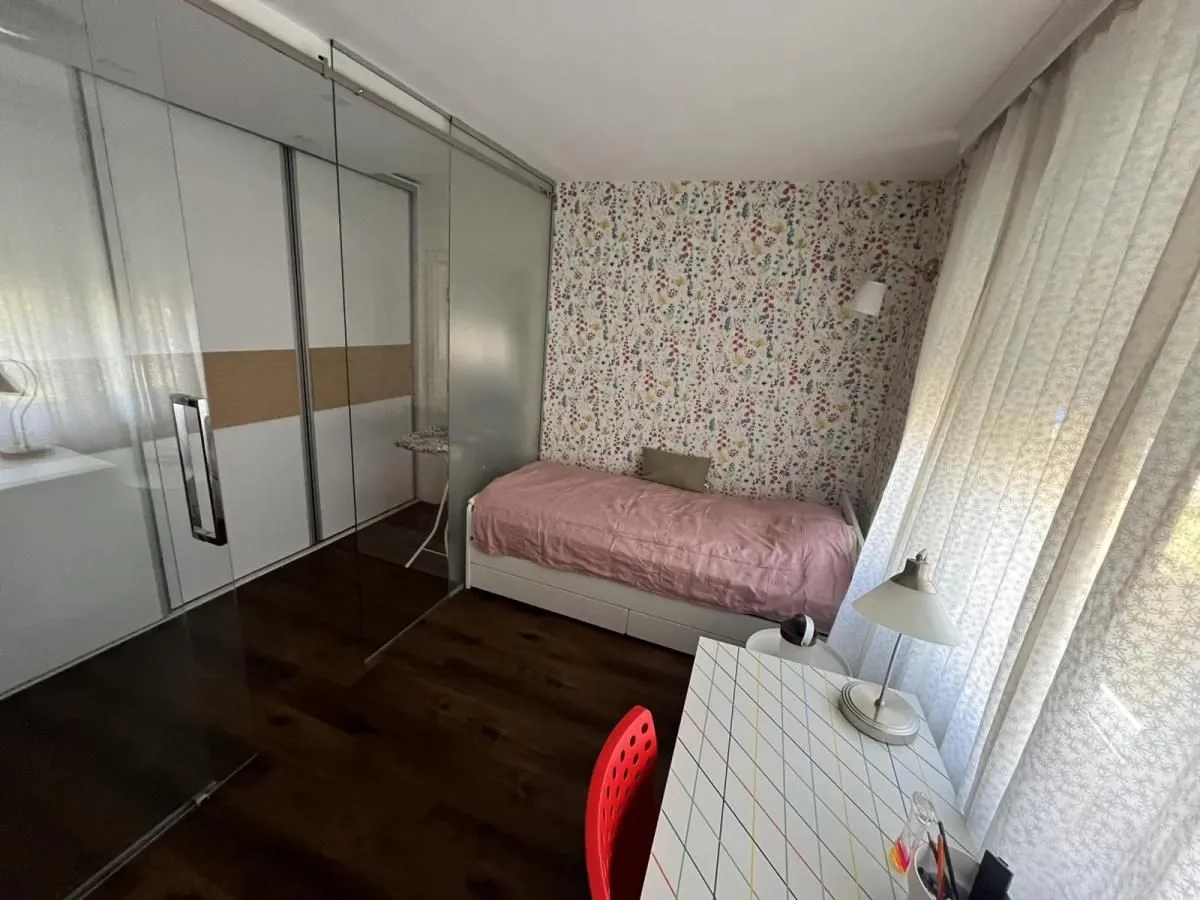 Dečja soba sa krevetom, radnim stolom i velikim ugradnim plakarom.