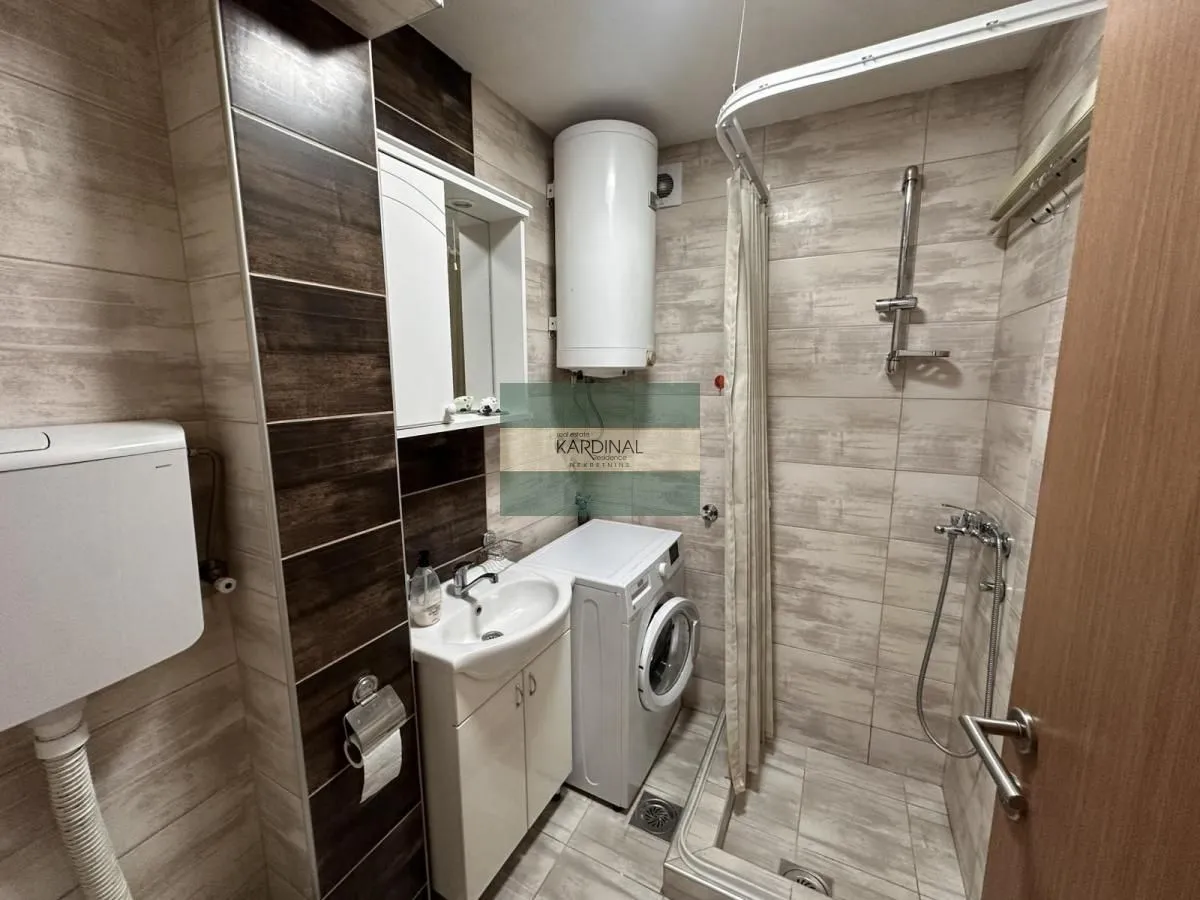 Bathroom equipped with a shower cabin, washbasin, and washing machine.