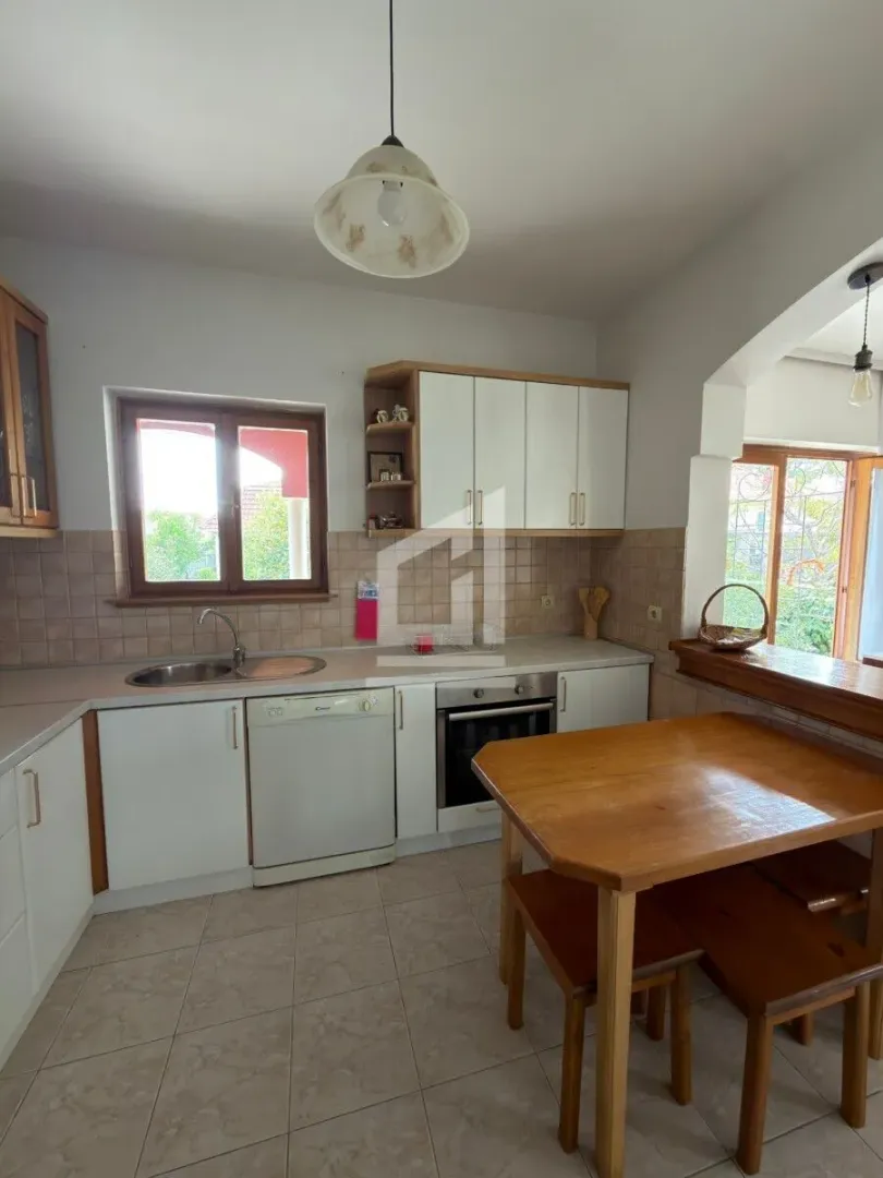 Kitchen equipped with white cabinets, a sink, and a wooden dining table.
