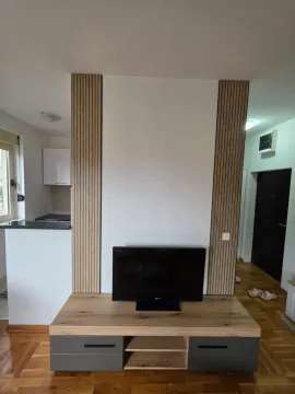 Living room with a TV stand and decorative wooden panels on the wall. - image 18
