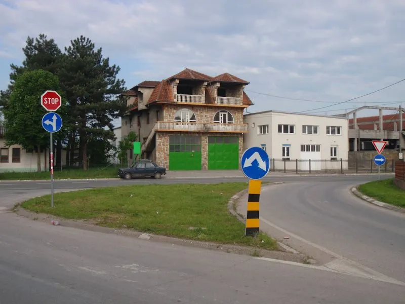 View of a multi-family house with green garage doors near an intersection.