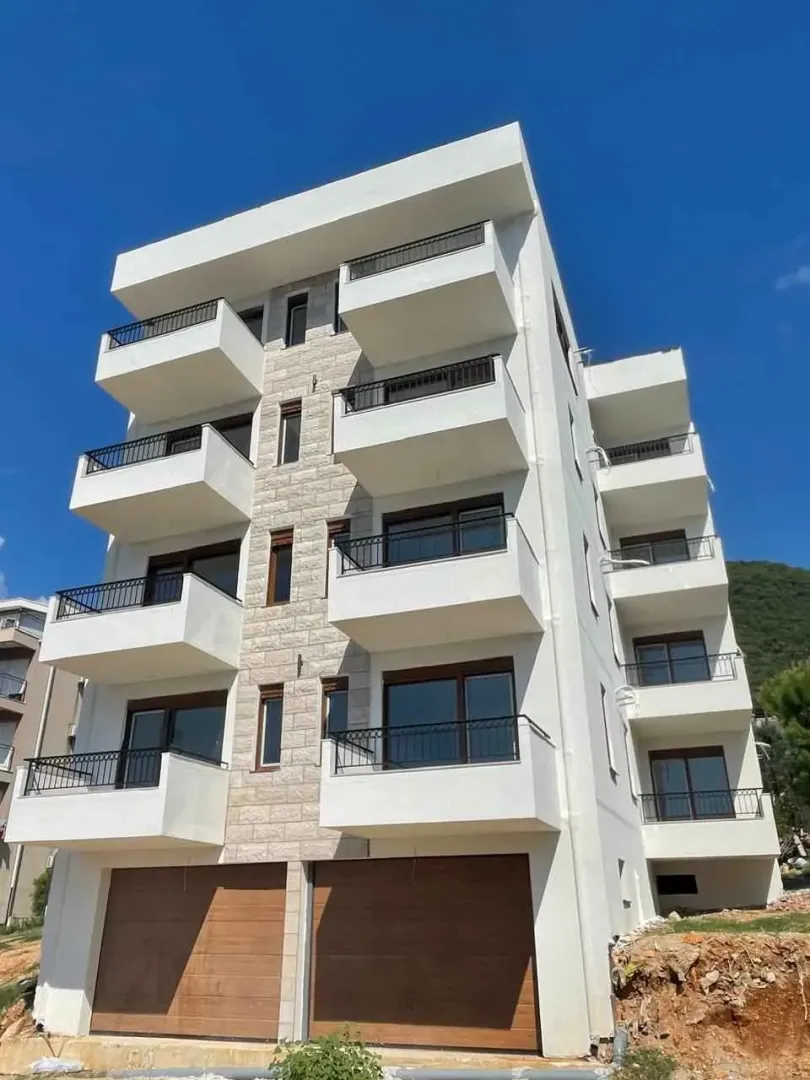 Prednji pogled na novu stambenu zgradu sa bijelom fasadom i balkonima.