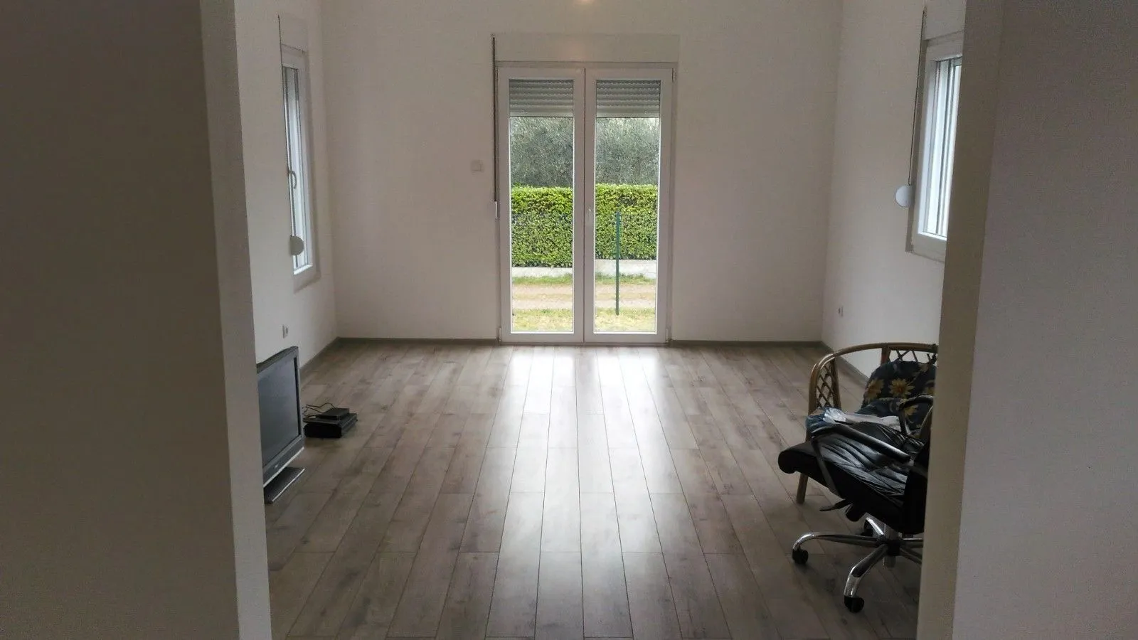 Bright empty room with laminate flooring and access to the yard.