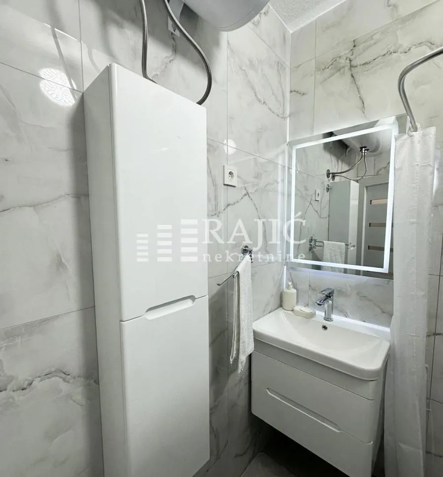 Modern bathroom with a sink, mirror, and white cabinetry.