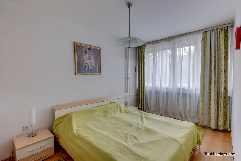 Bedroom with a double bed, bedside tables, and a window with curtains.