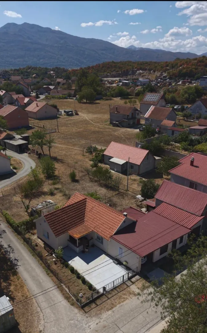 Pogled iz vazduha na kuću sa crvenim krovom i okruženje.