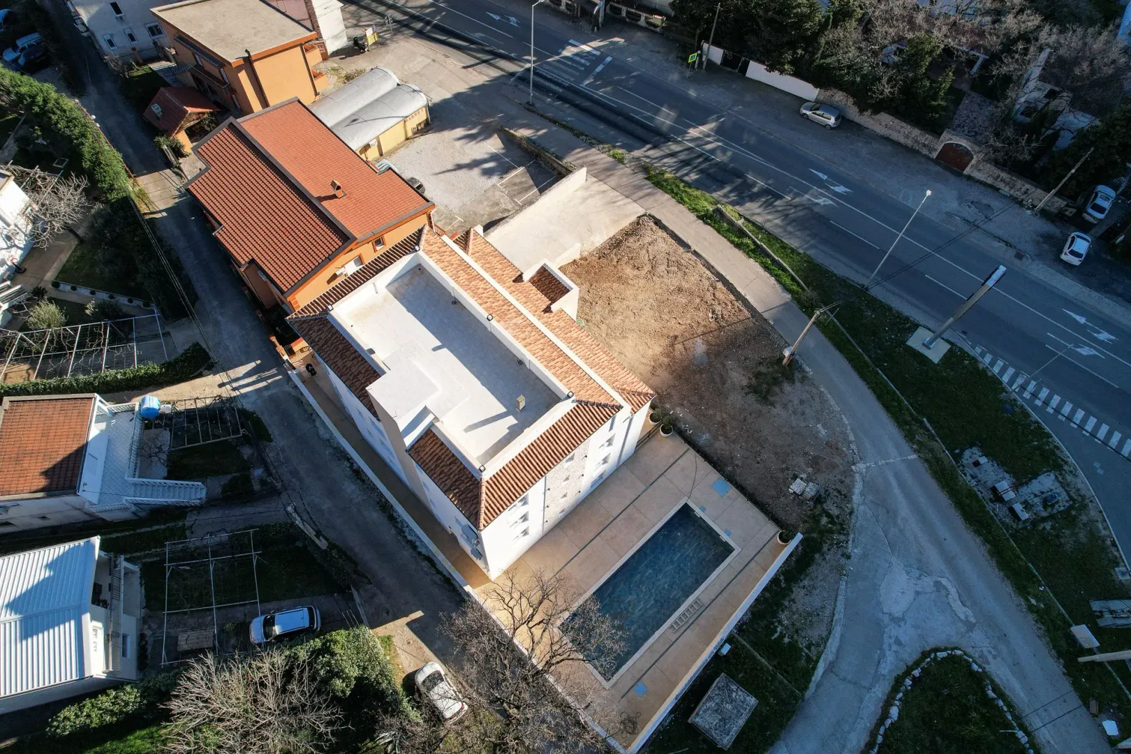 Pogled iz vazduha na stambenu zgradu sa bazenom i okolnim dvorištem.