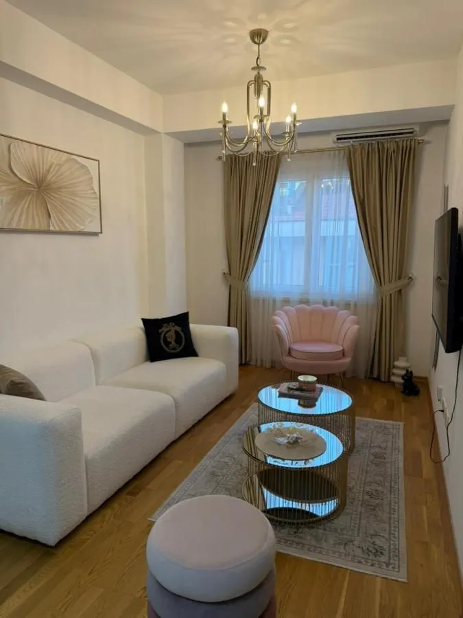 Dnevna soba sa bijelom garniturom, stočićima i lusterom.