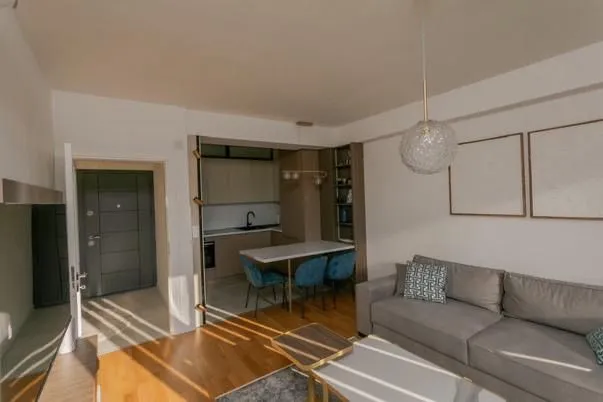 Modern living room with a sofa and a view towards the kitchen and dining area.