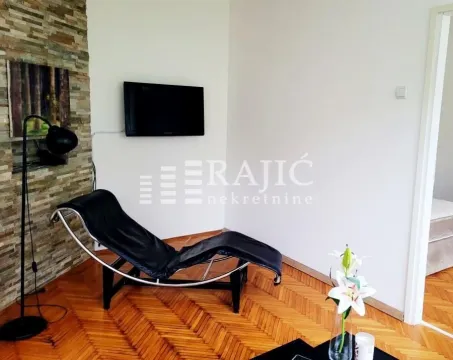 Living room with a chaise lounge, wall-mounted TV, and parquet flooring. - image 2