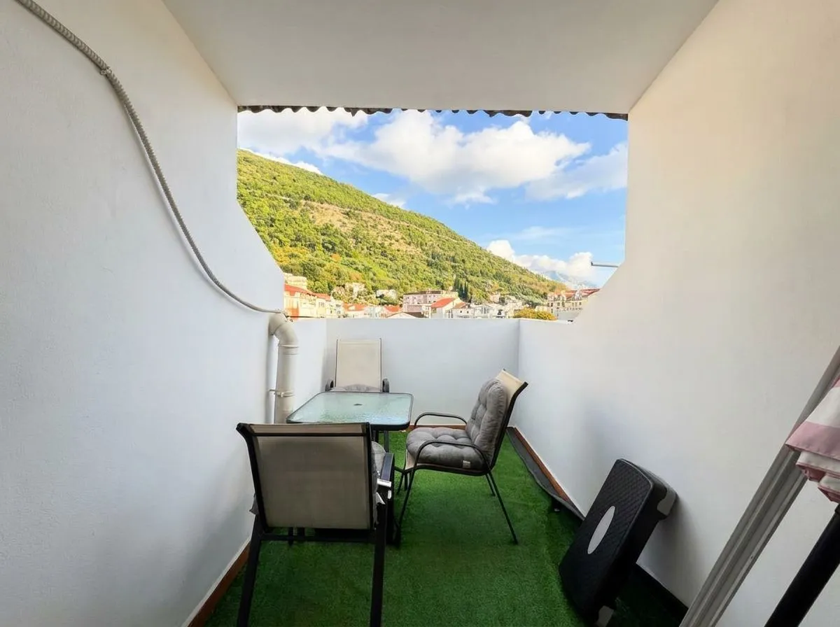 Natkriveni balkon sa garniturom za sjedenje i pogledom na brdo.
