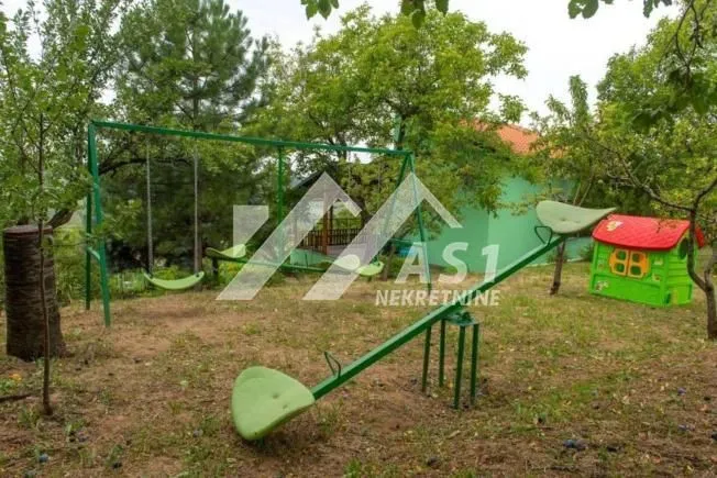 Dvorište sa igralištem, ljuljaškama i zelenilom.