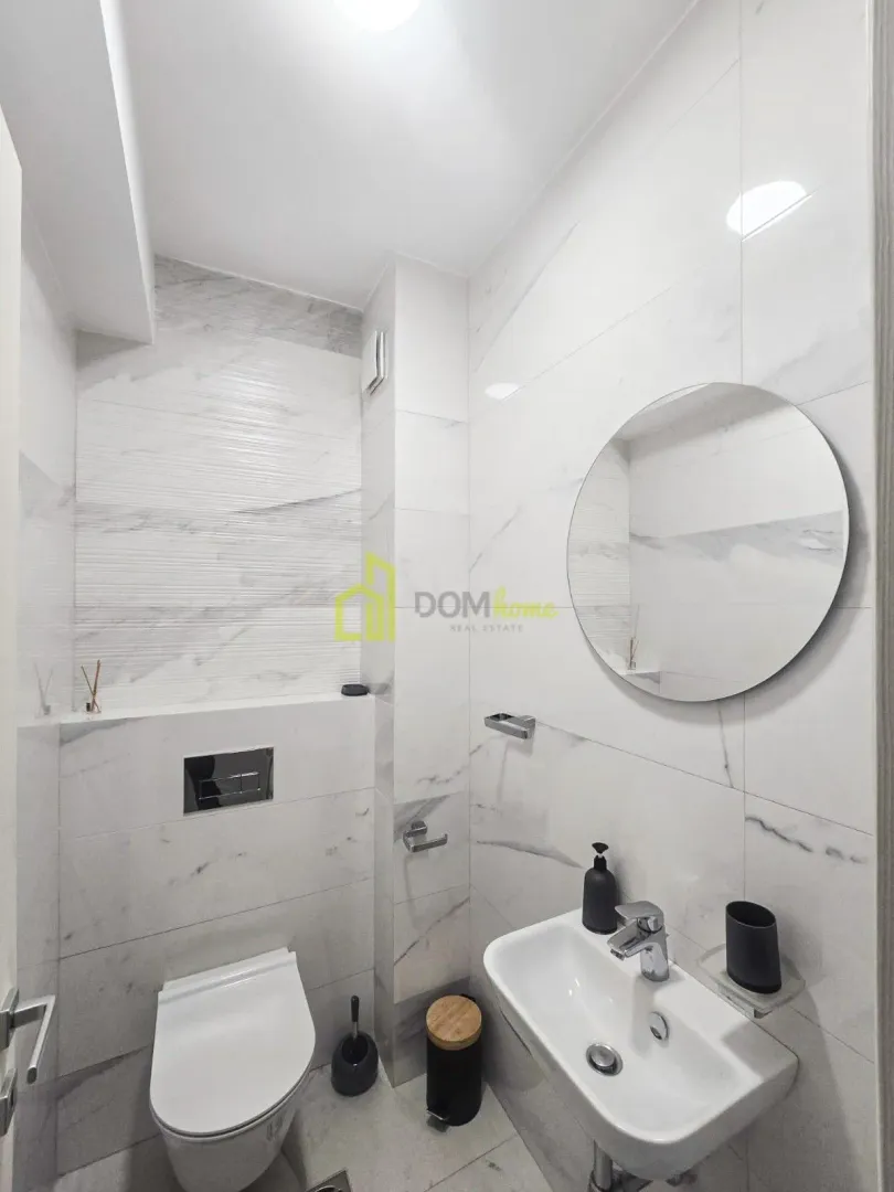 Modern bathroom with white tiles, washbasin and toilet.
