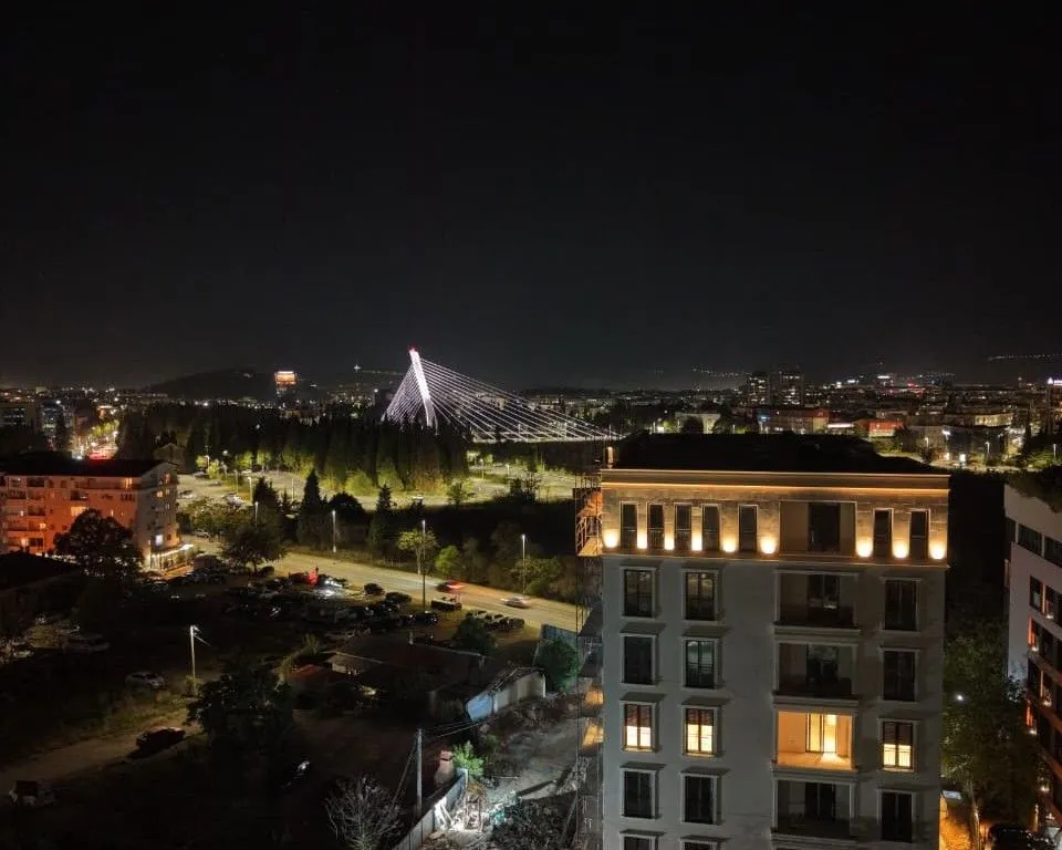 Noćni pogled sa terase na grad i osvijetljeni most.