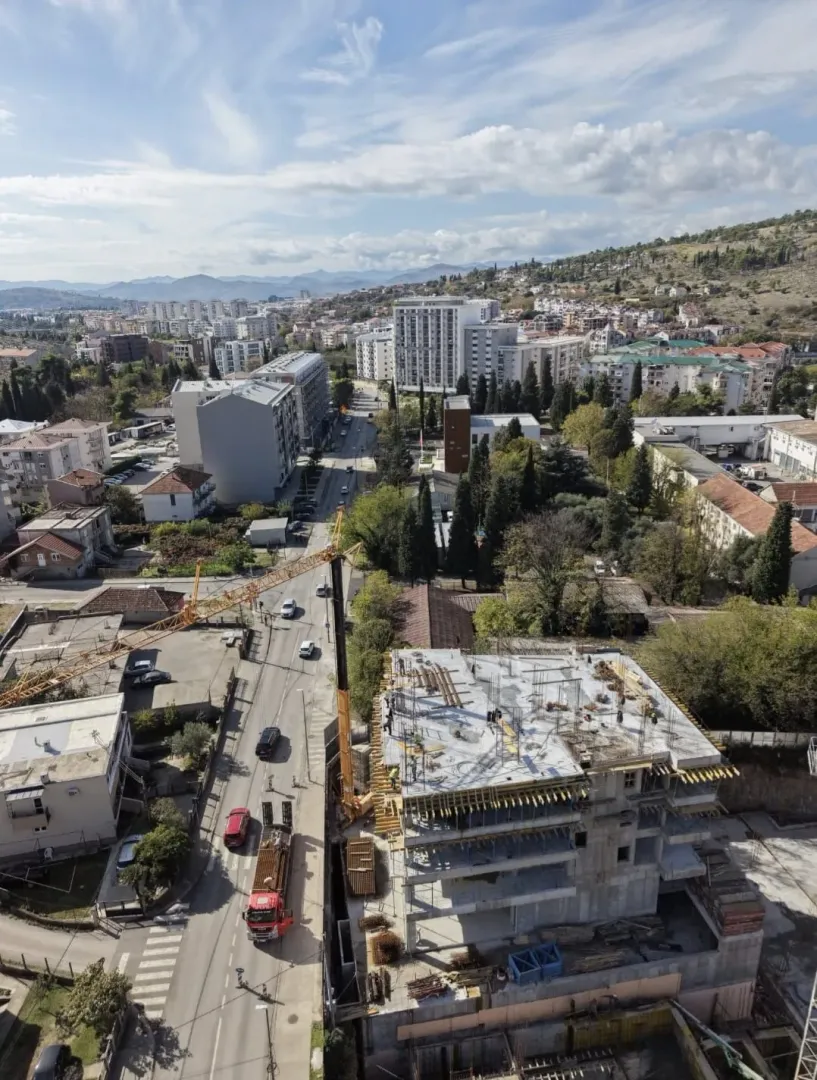 Aerial view of a building under construction in an urban area with surrounding buildings and streets.