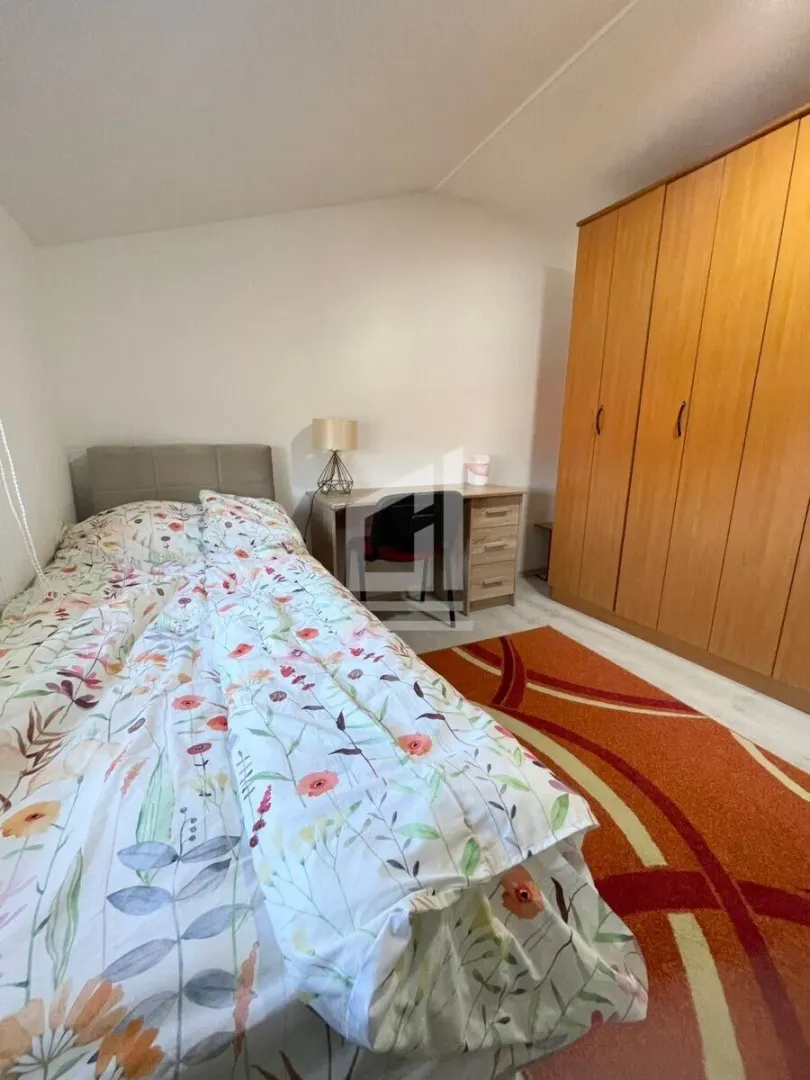 Bedroom with a bed, a desk, and a wooden wardrobe.