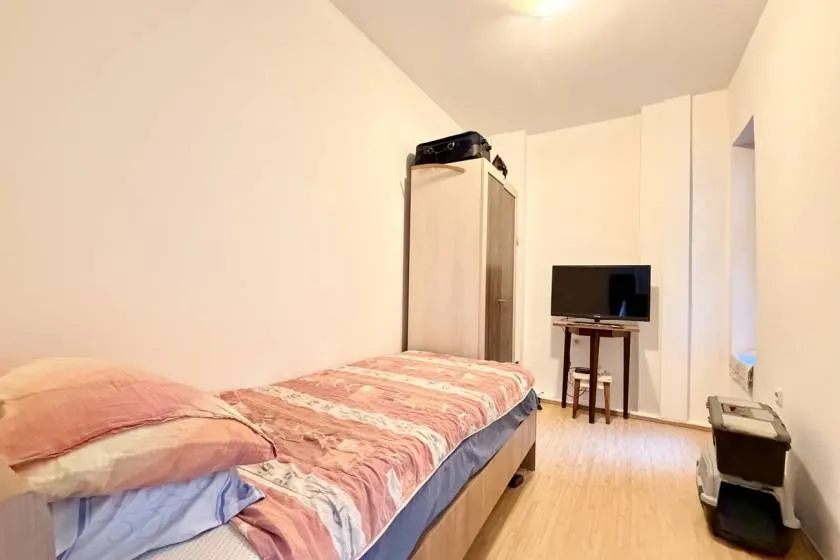 Manja spavaća soba sa krevetom, ormarom i televizorom.