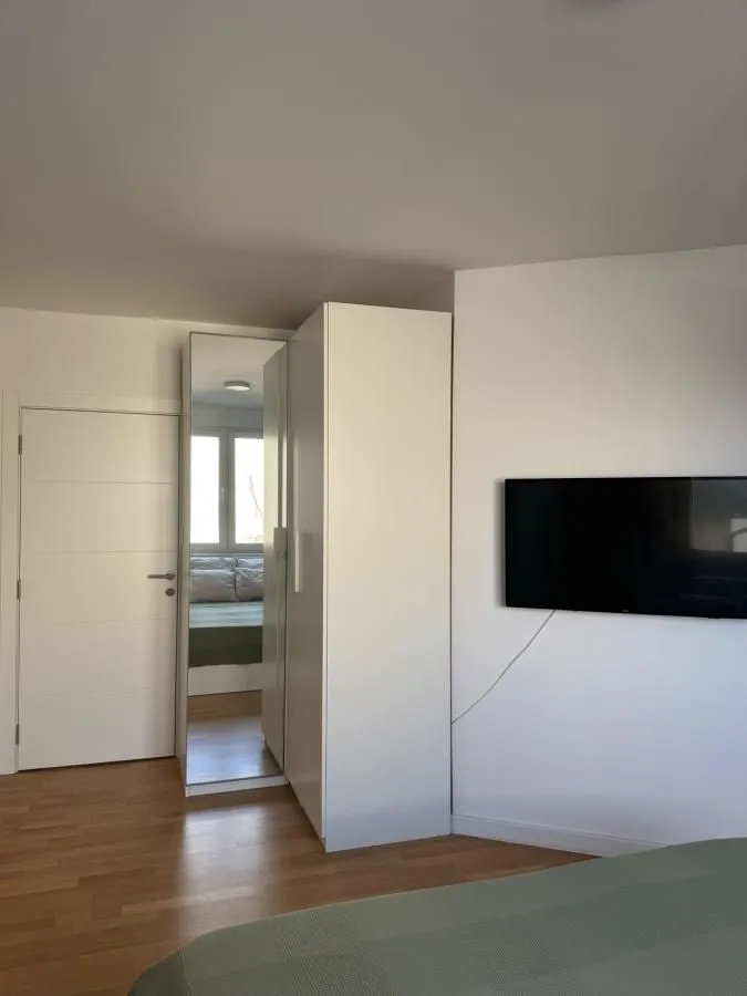 Spavaća soba sa krevetom, belim ormarom i televizorom na zidu.