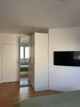 Spavaća soba sa krevetom, belim ormarom i televizorom na zidu. - image 13
