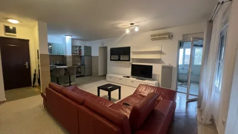 Spacious living room with a red corner sofa and a kitchen in the background. - image 2