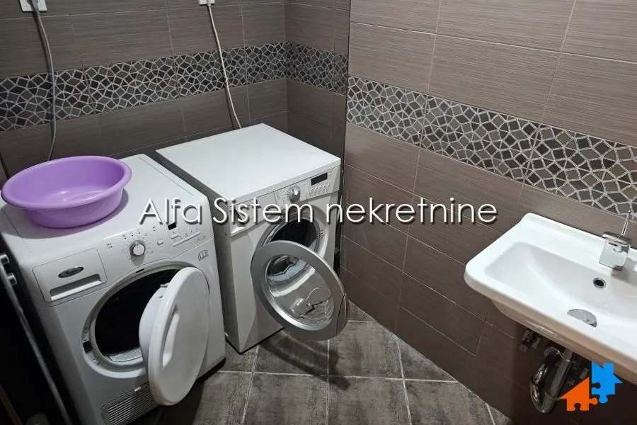 Bathroom with a washing machine, tumble dryer, and washbasin.
