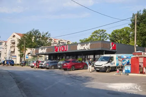 Pogled na spoljašnjost marketa sa parkingom i okolnim zgradama. - image 19