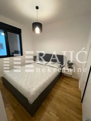 Modern bedroom with a double bed and parquet flooring.