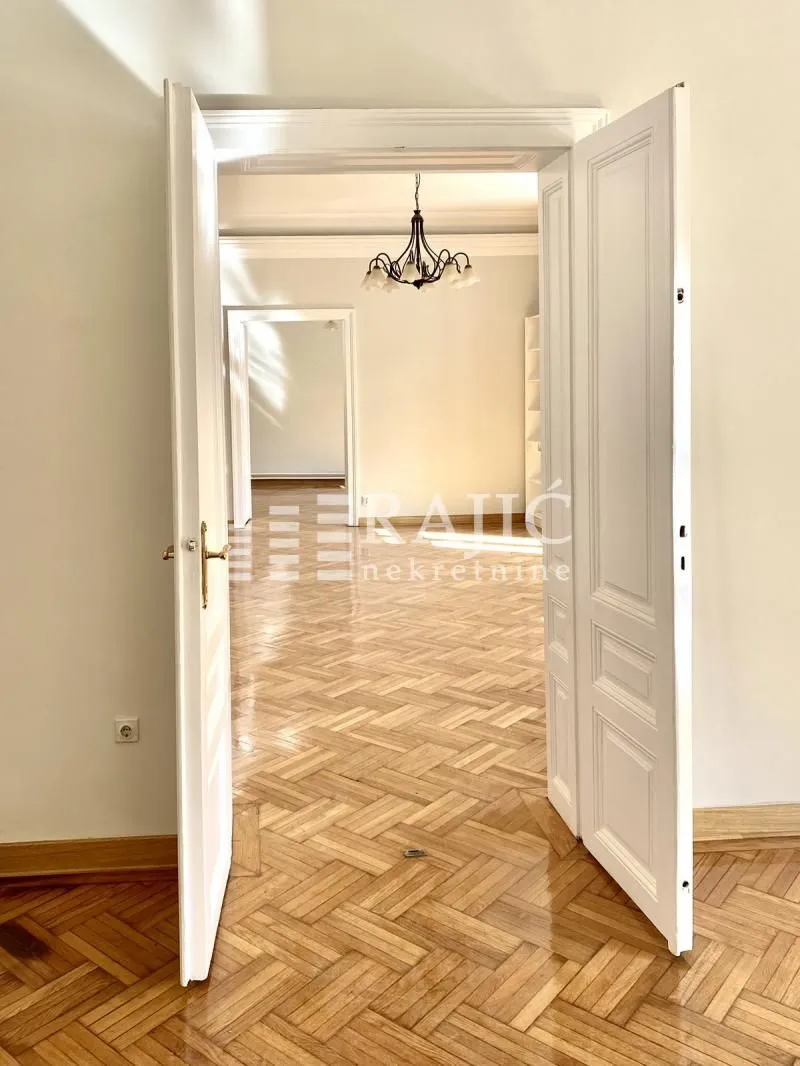 View through open double doors into a spacious room with parquet flooring.