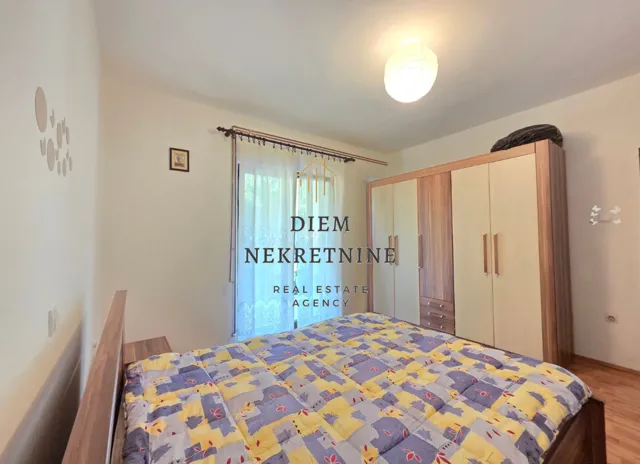Namještena spavaća soba sa bračnim krevetom i velikim plakarom.