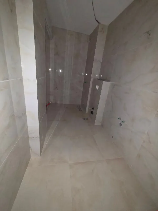Bathroom tiled in ceramic under construction with installed plumbing.