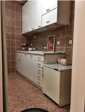 Mala, funkcionalna kuhinja sa bijelim elementima i smeđim pločicama. - image 6
