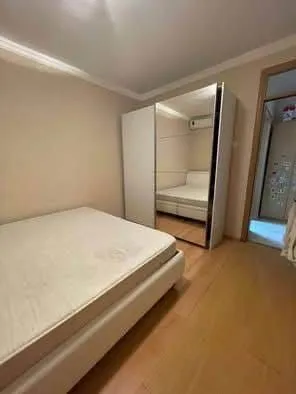Manja spavaća soba sa bračnim krevetom i velikim ormarom sa ogledalom.