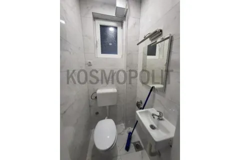 Small bathroom lined with marble tiles featuring a toilet, sink, and mirror. - image 4