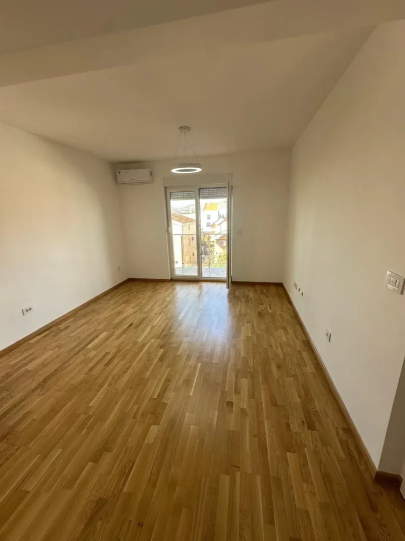 Empty room with wooden parquet flooring and access to the terrace.
