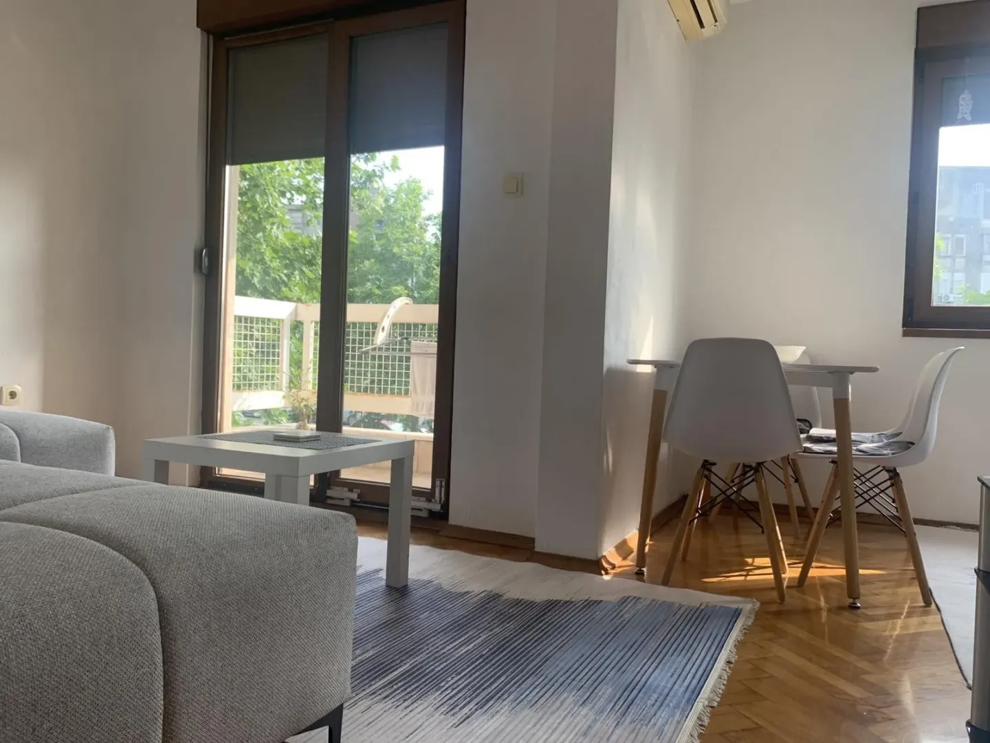 Svijetla dnevna soba sa trpezarijskim stolom i izlazom na balkon.