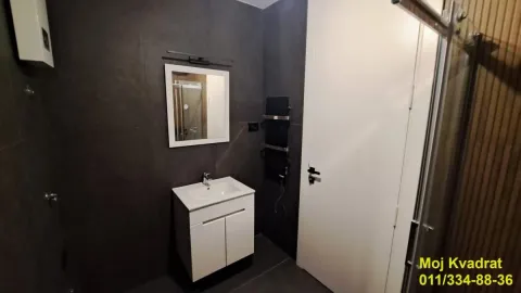 Moderno kupatilo sa tamnim pločicama, belim umivaonikom i ogledalom. - image 8