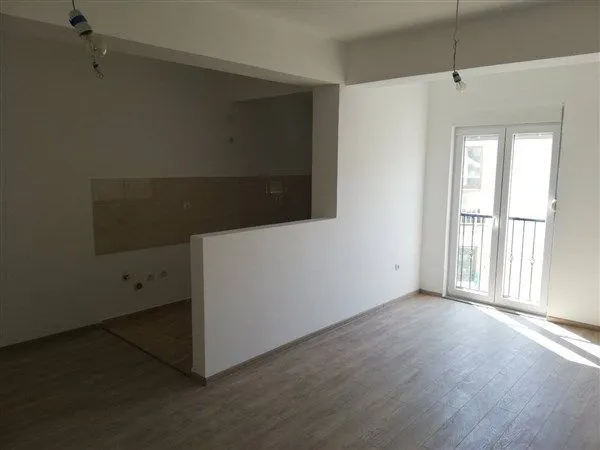 Prazna prostorija u novogradnji sa prostorom za kuhinju i izlazom na balkon.