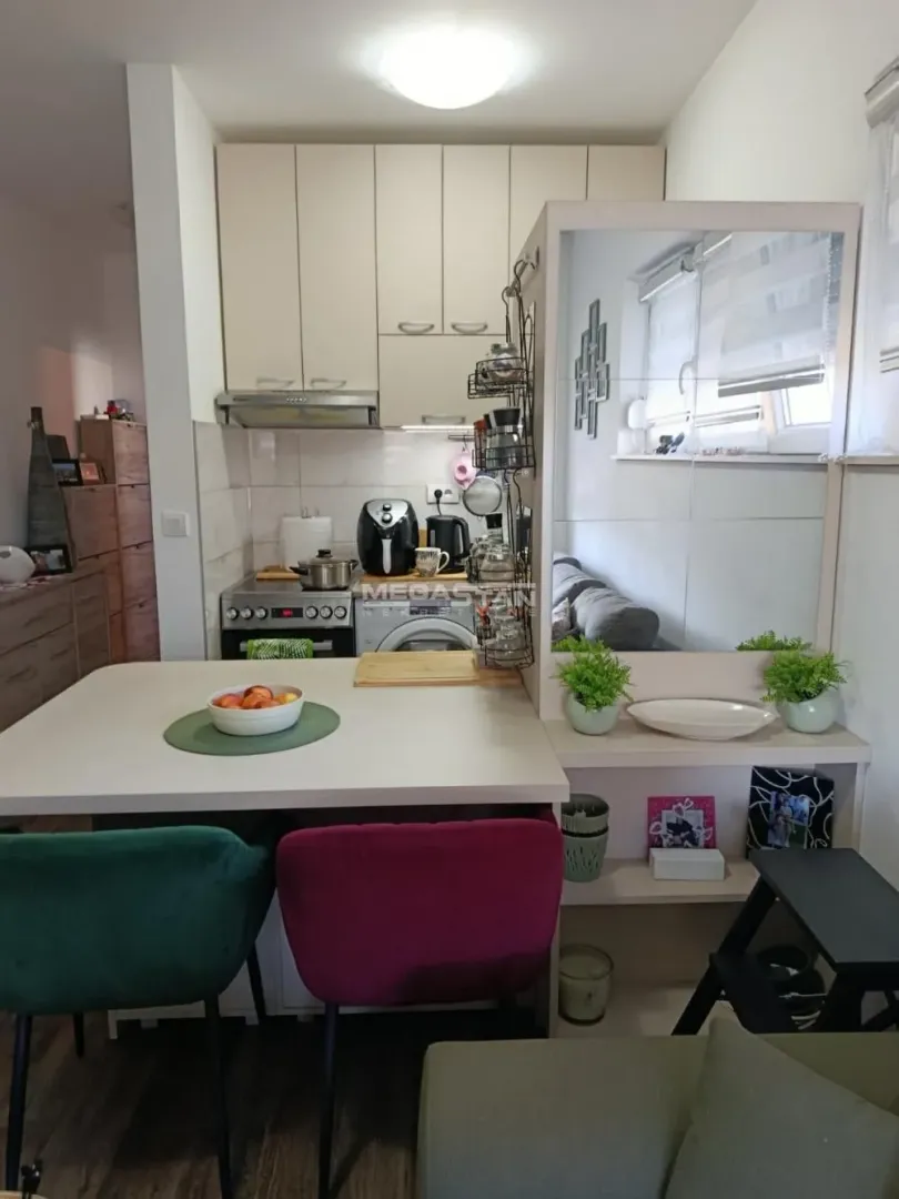 Small kitchen with a dining table and colorful chairs.