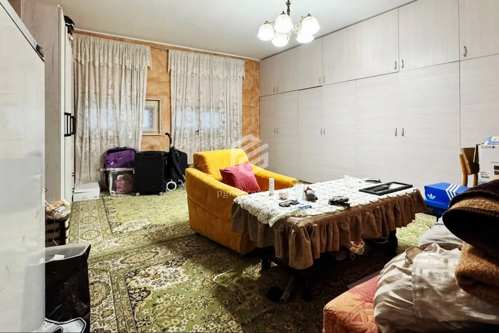 Dnevna soba sa žutom foteljom, velikim garderoberom i tepihom.