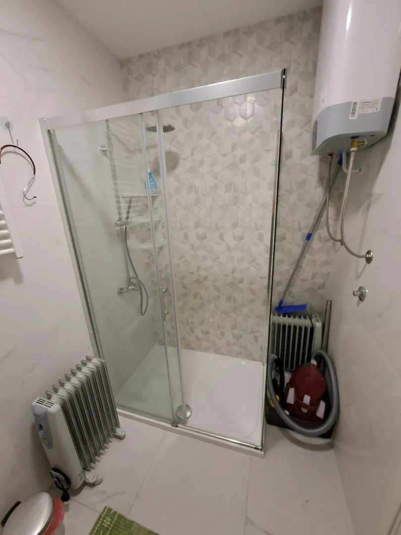 Kupatilo sa staklenom tuš kabinom i bojlerom.