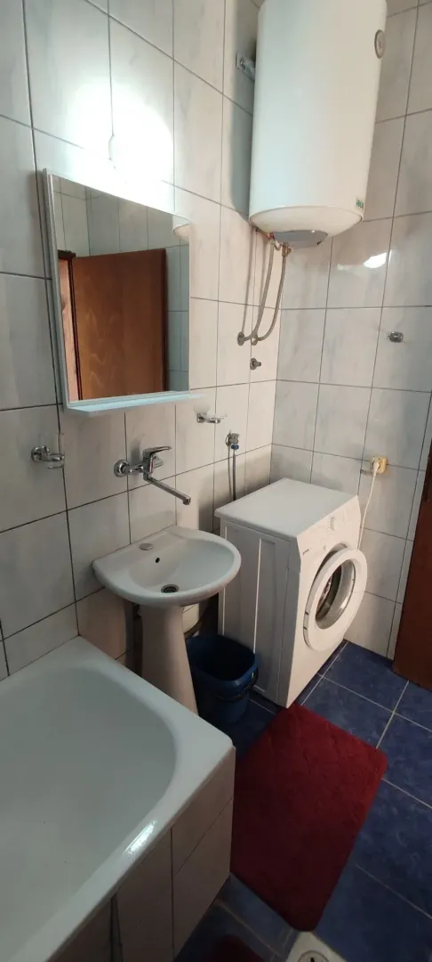 Manje kupatilo sa umivaonikom, kadom, veš mašinom i bojlerom.